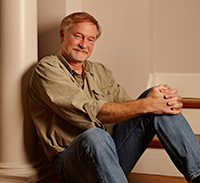 man sitting against a wall and smiling
