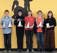 four middle-school boys and woman teacher holder triangular trophies