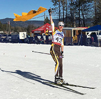 man on Nordic skis waving a University of Wyoming flag