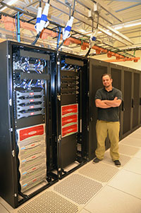 man standing next to computer servers