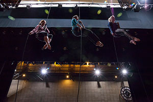 three dancers high in the air in lift harnesses