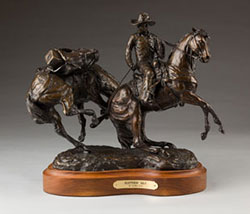 bronze statue of a cowboy on a horse leading a pack horse
