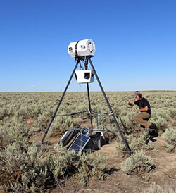 man working with a devise on a tall tripod outside