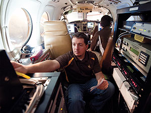 man in small area of airplane surrounded by electronic equipment