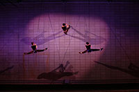 three dancers perform vertical dance on a wall