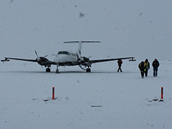 airplane on snowy runway wth people nearby