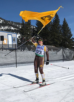 cross-country skier holding a University of Wyoming banner
