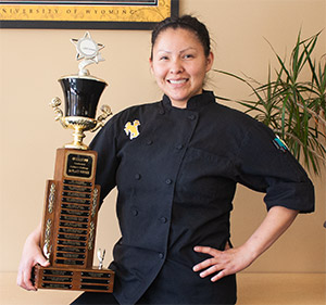 woman in chef's clothing holding trophy