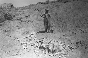 old black and white photo of a man with a pile of bones