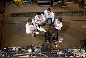 overhead view of four people in white coats looking at equipment