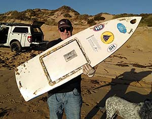 man holding remains of miniature sailboat