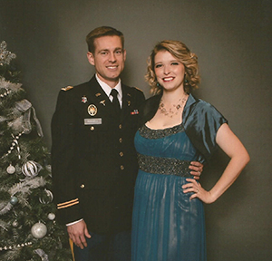 man in uniform and woman in evening dress posing by a Christmas tree