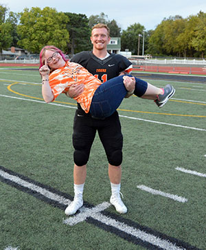 man carrying a young woman on a football field