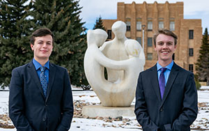 Two men standing out side in front of a sculpture