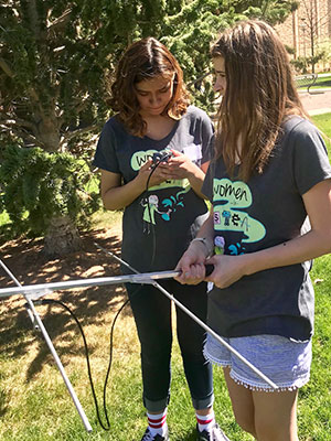 two young women working with equipment outside