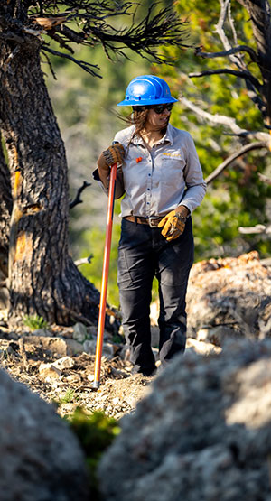 womnan with hardhat, gloves and tool on mountian trail