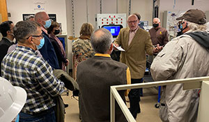 group of people on a tour of a lab with electronic equipment