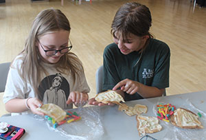 two girls at a table looking at impressions in bread slices