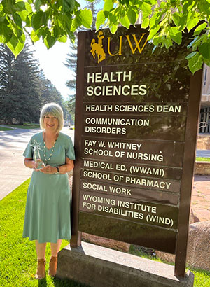 woman standing outdoors beside a large sign