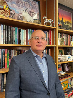 man standing in front of shelves with books and memorabilia