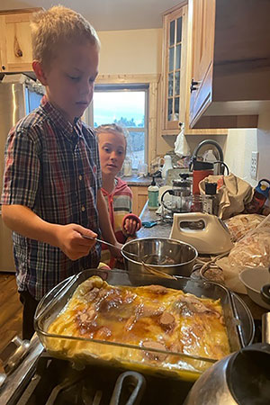 a young boy cooking as a girl looks on
