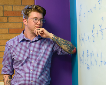 man looking at white board with equations on it