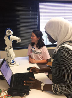 a girl and a young woman examine a robot
