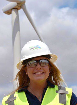 woman in a hard hat in front of a wind turbine