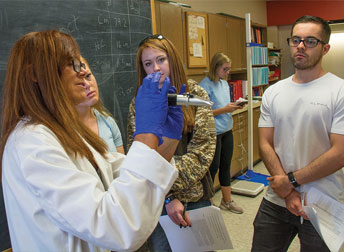 woman demonstrating lab techniques to small group of students