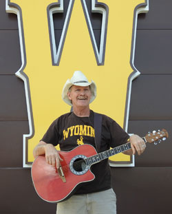 man with a guitar in front of a giant yellow W
