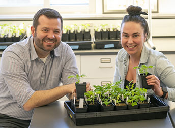 man and woman with a tray of seedlings in front of them