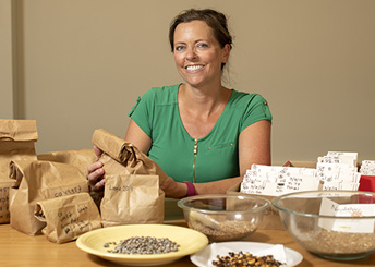 woman sitting at a table with bags and bowl of beans