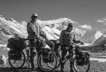 two men on bicycles with mountains in the background