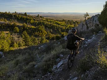 person mountain biking on the side of a rocky hill