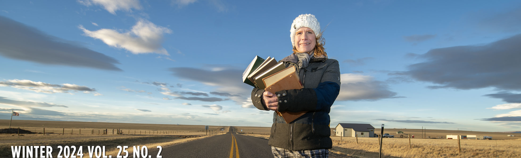person standing in front of an open highway holding a stack of books