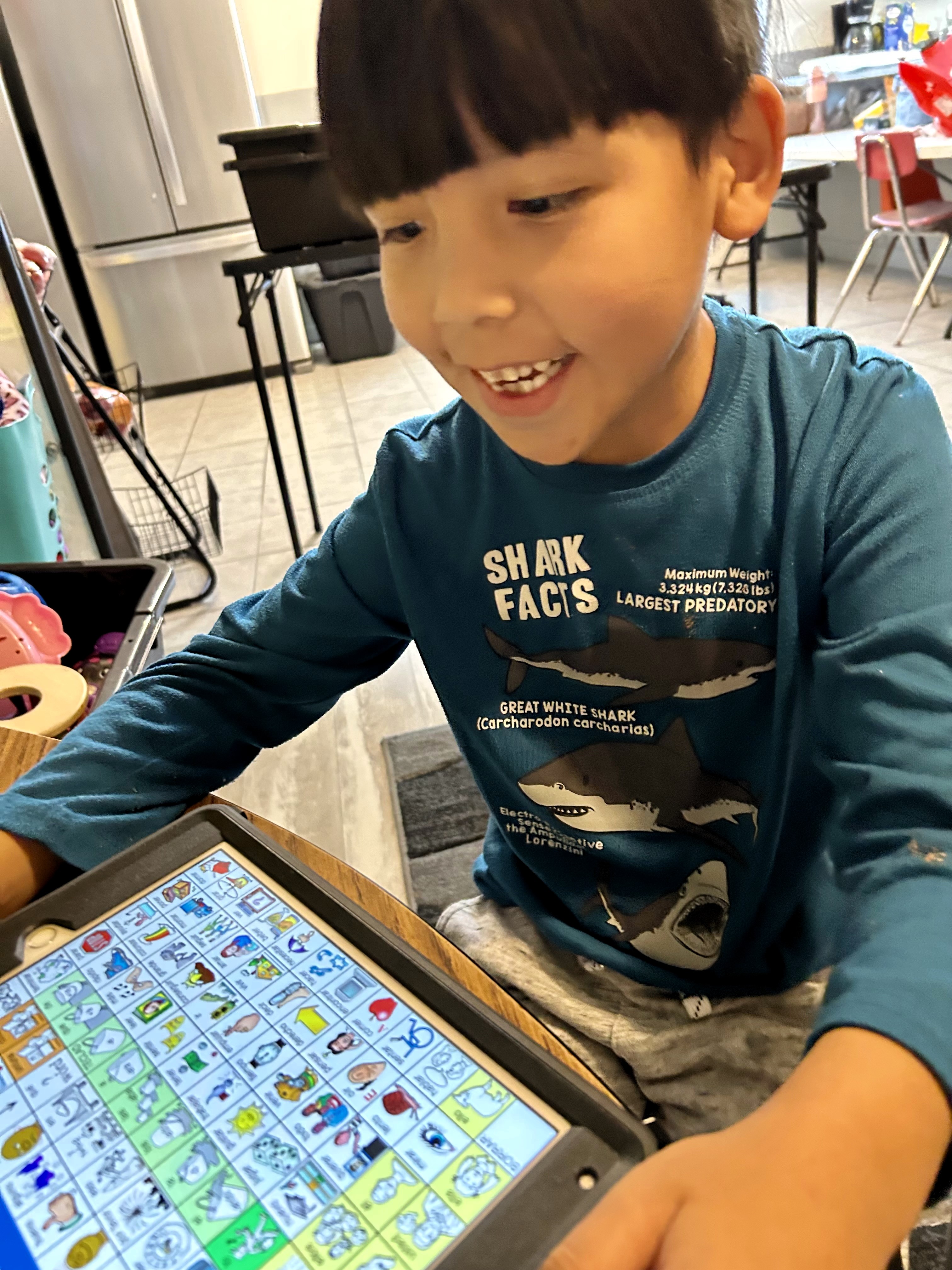 Young boy smiling using an ipad for communication
