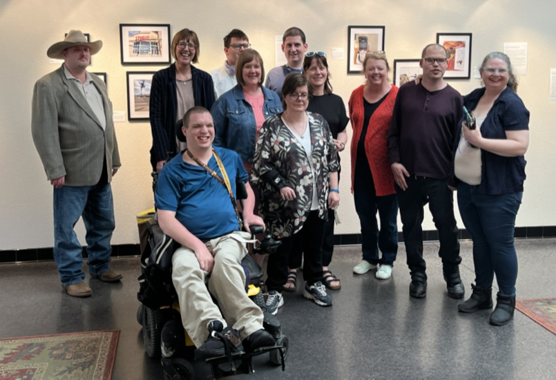 A WIND staff member and WIND participants sit gather together at an art exhibit