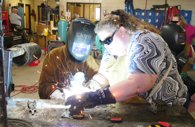 an adult helps a child practice welding