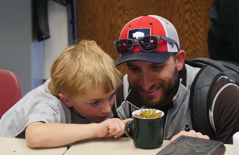 an adult and child look at a mug with a cactus in it