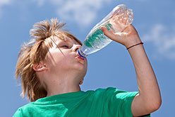boy in a green t-shirt drinking water