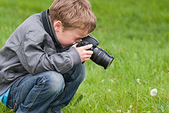 a boy with a camera in a grassy field