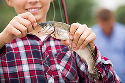 boy removing a fly from a brook trout's mouth