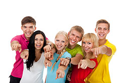 Six teens smiling and pointing at the camera