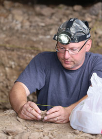 man with headlamp examining a rock