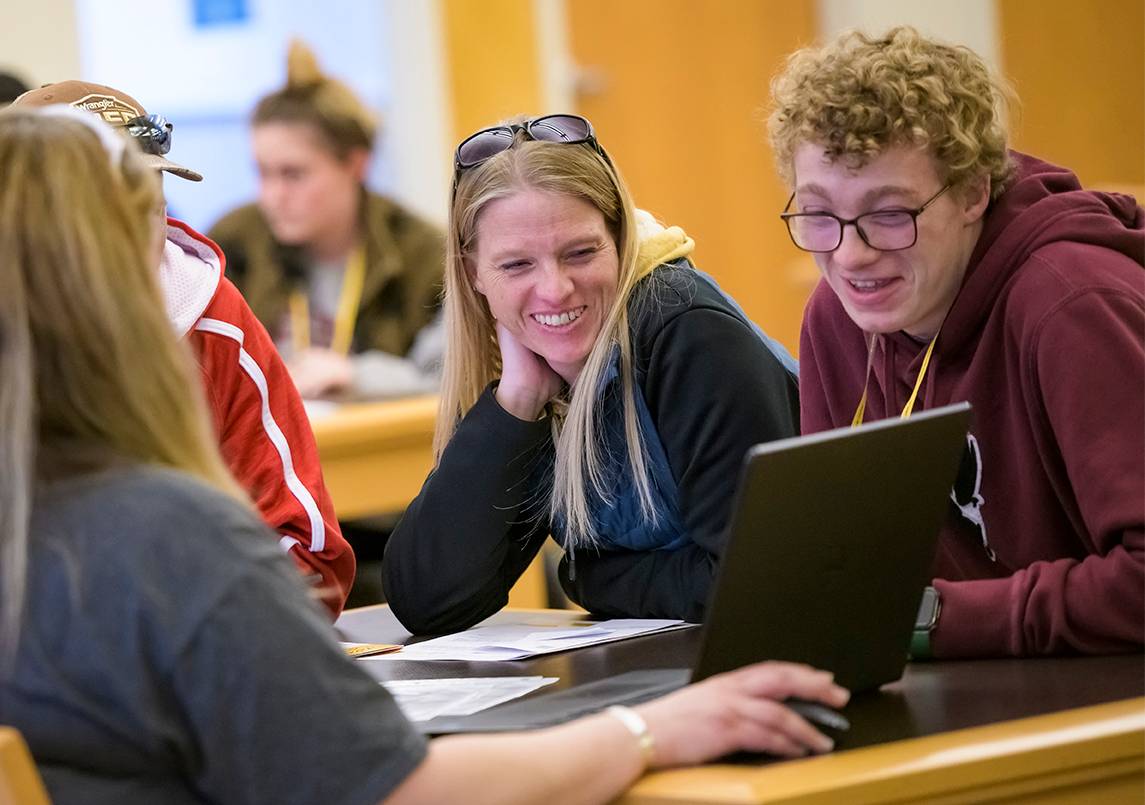 Students looking at laptop smiling