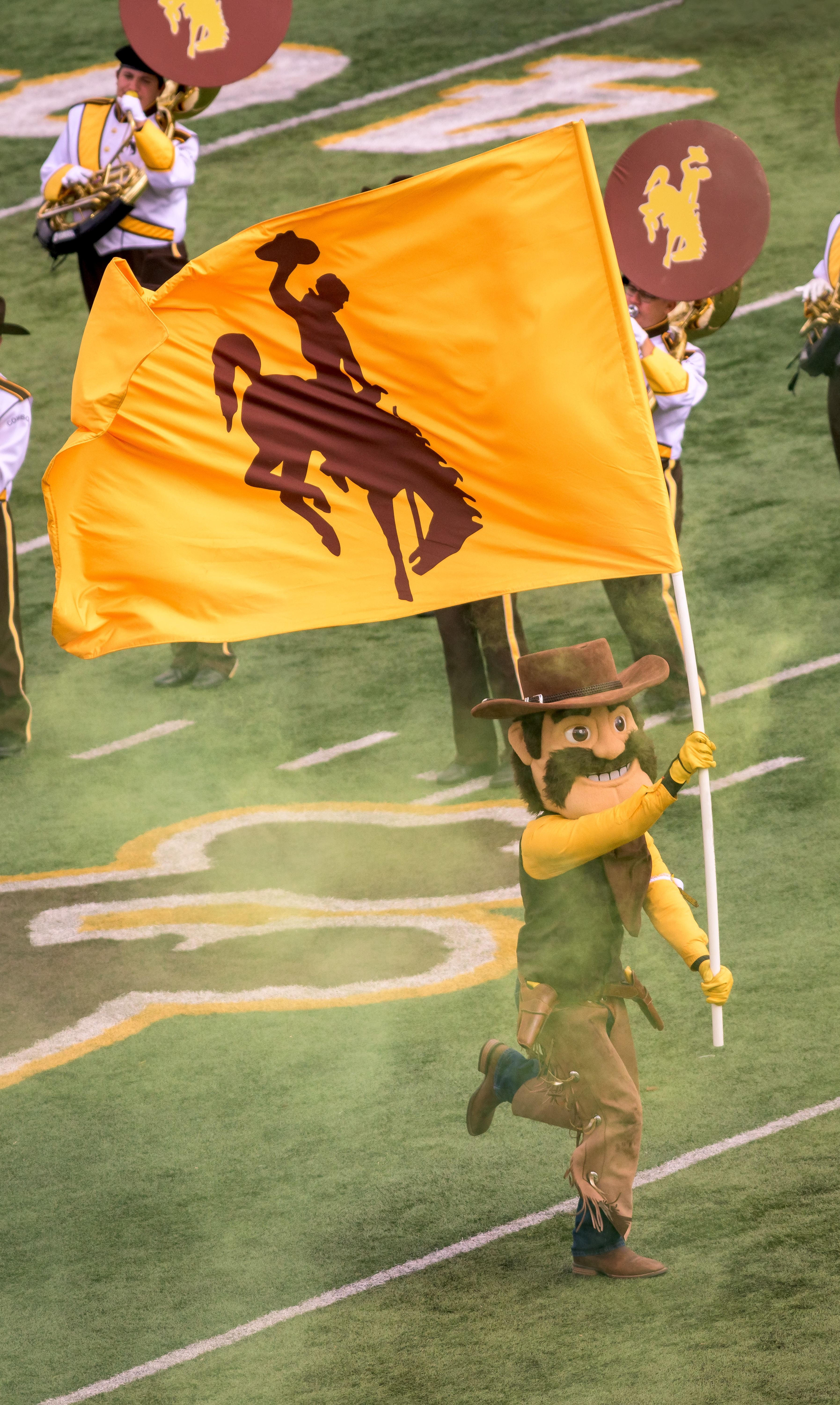 Pistol Pete running onto football field with UW flag
