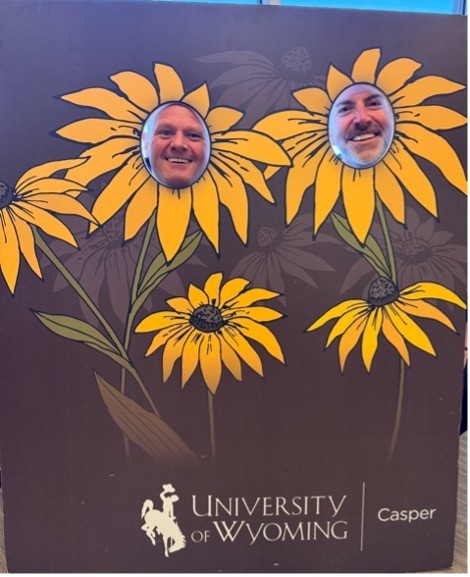 photo of two people behind a flower cut out board