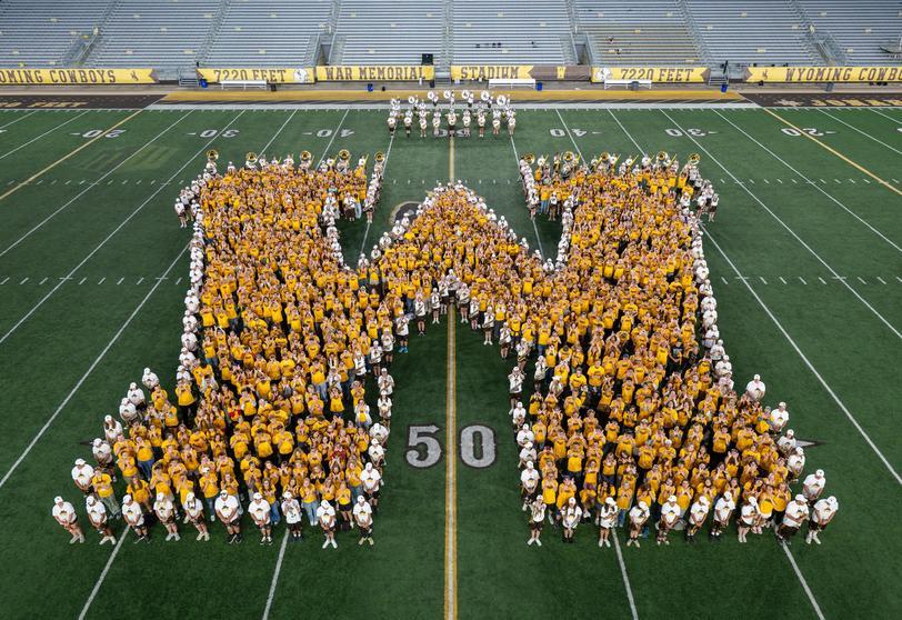 A large group of student form a large "W" on a football field.