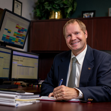 A business manager sitting in his office with his computer in the background