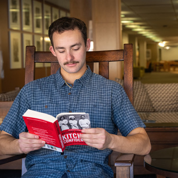 A student reading a book in Coe Library